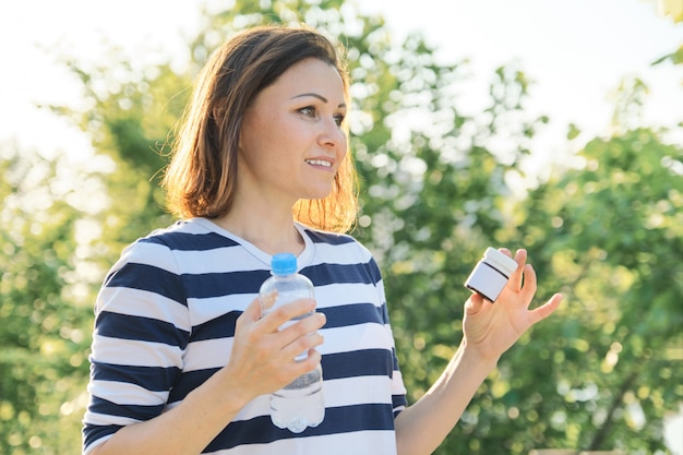 薬、ビタミン、サプリメントの薬瓶を持つ成熟した女性