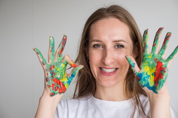 Mature woman with painted hands shows sign ok in studio