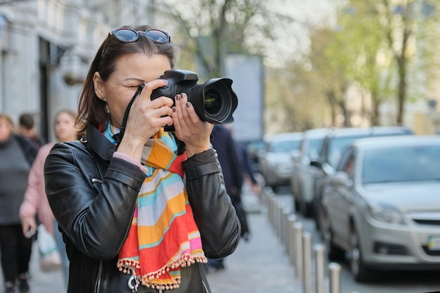 Mature woman with photo camera photographing on the street