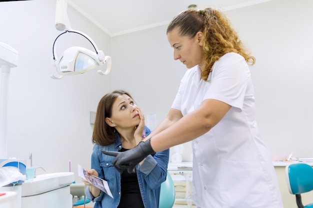 Mature woman with toothache talking to professional dentist,