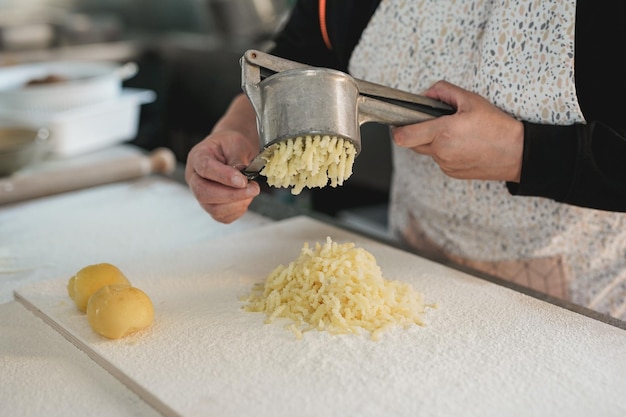 Mature woman working inside pasta factory doing fresh made gnocchi