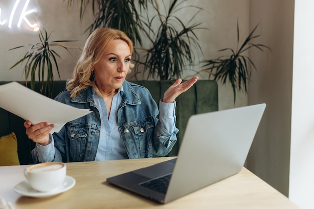 Mature woman working on laptop in cafe