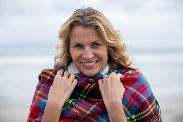 Photo mature woman wrapped in shawl on the beach