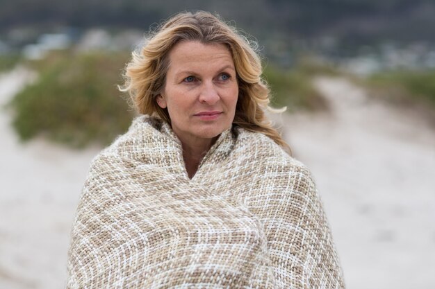 Mature woman wrapped in shawl on the beach