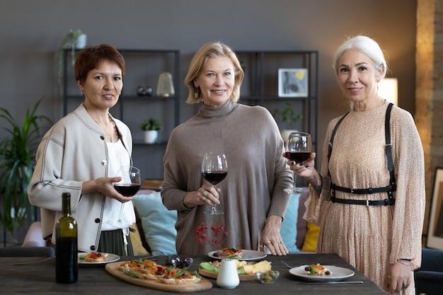 Mature women drinking wine at dinner party