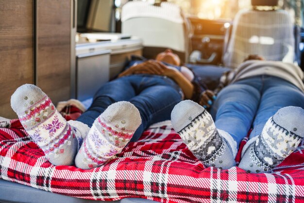 Mature women sleeping inside mini van camper wearing Christmas warm socks Focus on feet