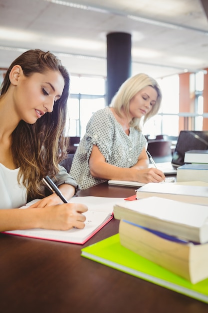 Matures females students writing notes at desk