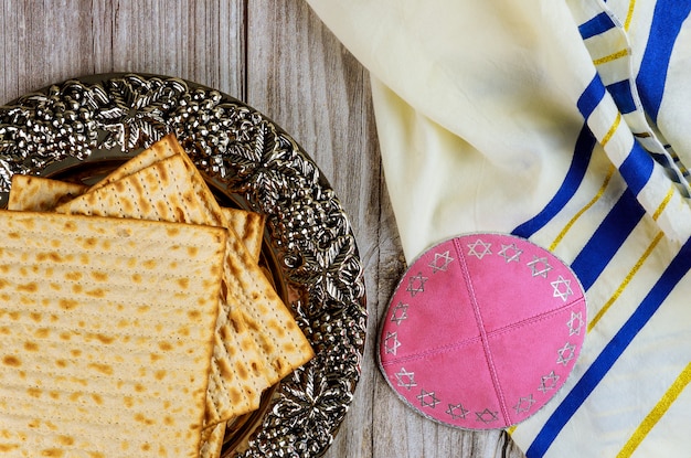 Matza, tallit and kippa on wooden background.