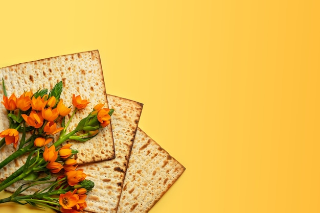 Matze en bloemen op yllow achtergrond, bovenaanzicht. Pascha (Pesach) Seder Pesah viering concept (Joodse Pascha vakantie). Bovenaanzicht