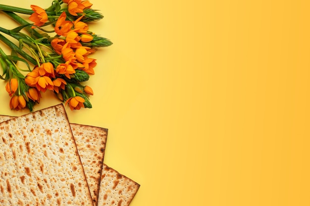 Matze en bloemen op yllow achtergrond, bovenaanzicht. Pascha (Pesach) Seder Pesah viering concept (Joodse Pascha vakantie).