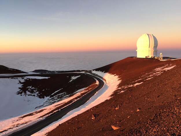 Photo mauna kea observatory on volcanic mountain by cloudscape against sky during sunset