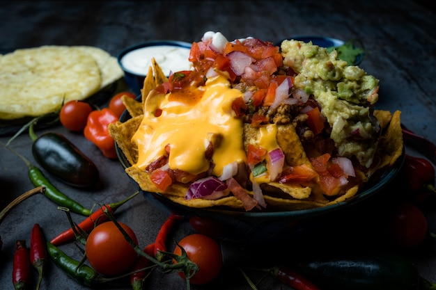 Maxican food nachos with cheese and guacamole and pico de gallo sour cream and tomato cherry