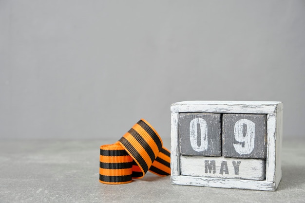 May 09 wooden calendar and St George ribbon gray backgroundConcept for Victory Day over fascism