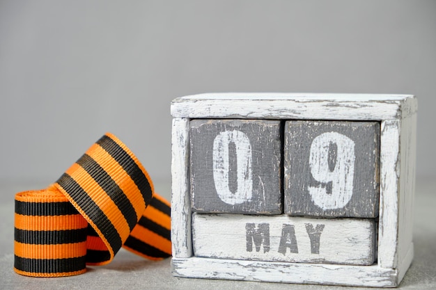 May 09 wooden calendar and St George ribbon gray backgroundConcept for Victory Day over fascism