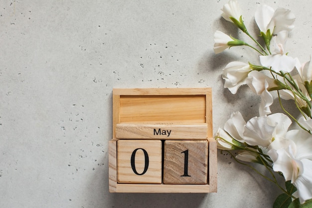 May 1 on a wooden calendar, next to a white flower