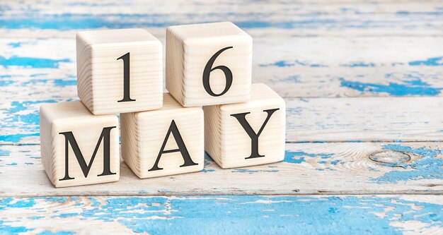 写真 5月16日。古い青い木製の背景に5月16日の日付の木製の立方体。
