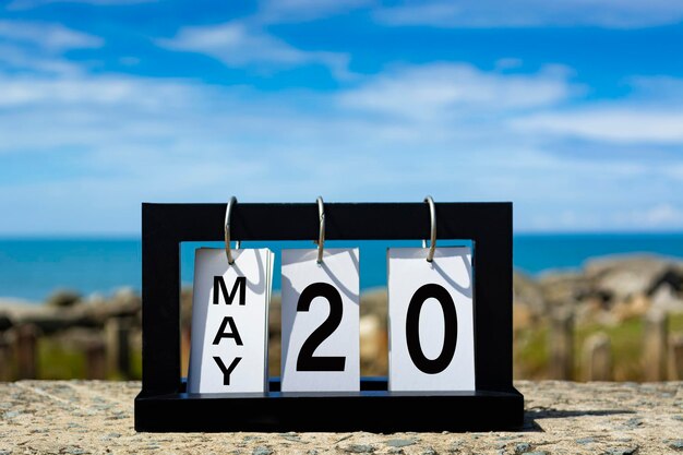 Foto testo della data di calendario del 20 maggio su cornice di legno con sfondo sfocato dell'oceano concetto di data di calendario