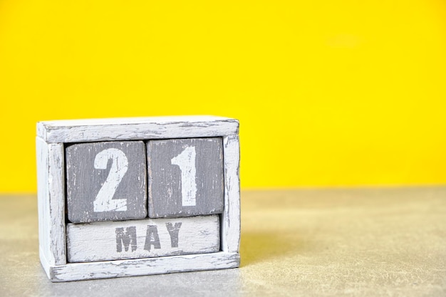 5 月 21 日のカレンダーは、木製の立方体の黄色の背景を作ったあなたのテキストのための空のスペース