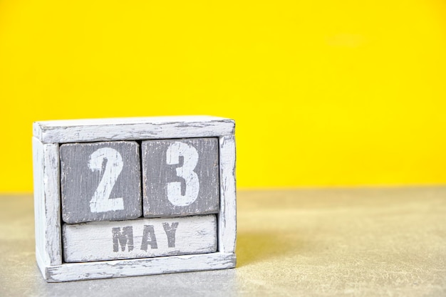 Foto calendario del 23 maggio realizzato con cubi di legno sfondo giallocon uno spazio vuoto per il testo