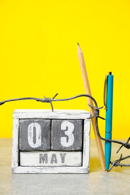 カレンダーの 5 月 3 日有刺鉄線ボールペンと鉛筆の黄色の背景プレスの自由の日のための概念