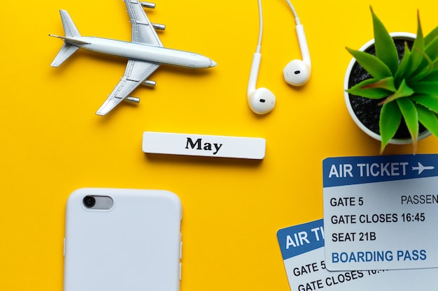 Фото Концепция каникул в мае - игрушка самолет с билетами на желтой стене.