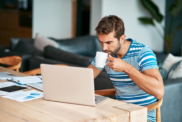 Maybe some coffee will help Cropped shot of a handsome young male entrepreneur drinking coffee while working from his home office