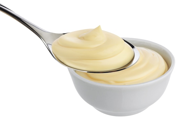 Mayonaise in lepel en kom op wit wordt geïsoleerd