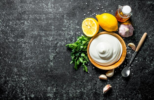 Mayonnaise in a plate with herbs garlic slices and lemon slices