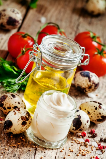 Mayonnaise sauce with quail eggs in a glass jar with vegetables herbs and spices selective focus