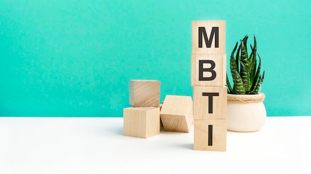 Photo mbti word is written on wooden cubes on a green background closeup of wooden elements in the background is a green flower