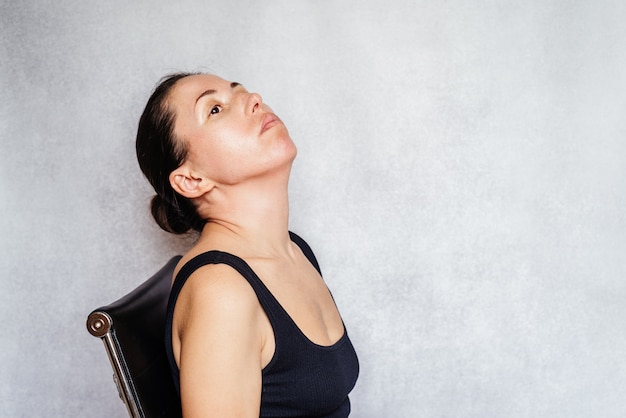 Photo mckenzie method exercise to relieve neck pain, a woman gently rotates her head while doing neck pain relief exercises