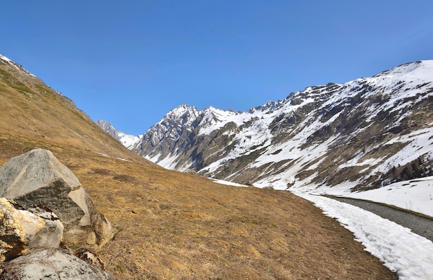 Луг и вершина горы со снегом и рекой весной в альпийском ландшафте