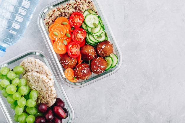 Meal prep lunchbox containers met quinoa gehaktballen komkommers wortelen sesam en pompoenpitten