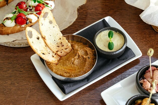 A meal on a table with a bowl of food and a bowl of dip.