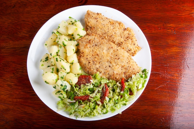 meal with fish fillet breaded with potatoes and salad