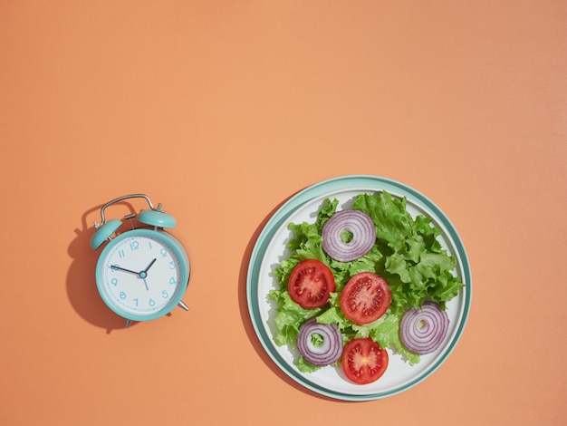 食事時間の目覚まし時計とサラダ プレート健康的な食事の概念ダイエット減量と断続的な断食トップ ビュー コピー spaceorange 背景