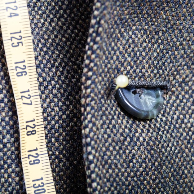 Measure tape and buttoned button on green jacket