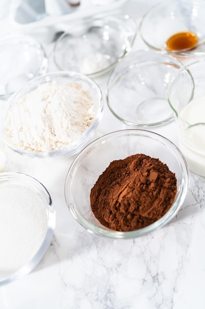 Photo measured ingredients in glass mixing bowls to prepare chocolate cupcake.