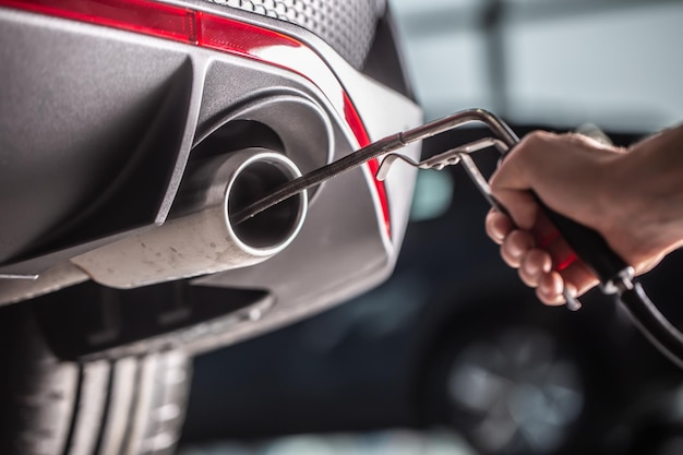 Measurement of exhaust emissions at the technical inspection station A car repairman applies a probe to the exhaust