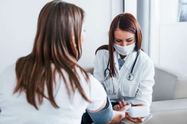 Misurazione della pressione sanguigna la giovane donna ha una visita con il medico femminile nella clinica moderna