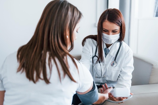 measuring blood pressure young woman have a visit with female doctor in modern clinic