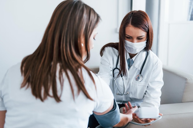 Measuring blood pressure Young woman have a visit with female doctor in modern clinic