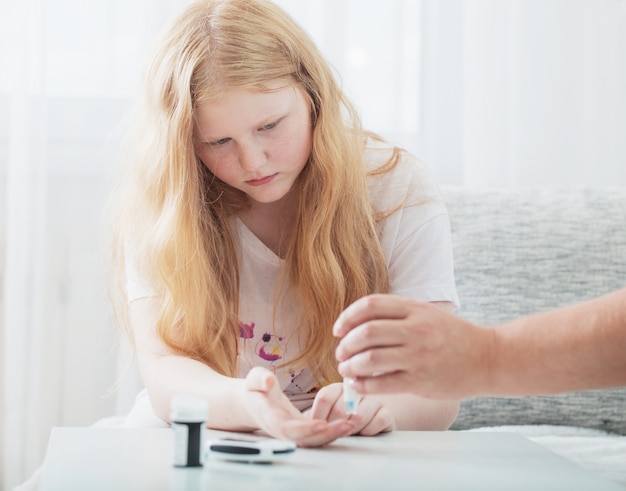 グルコメーターで十代の少女の血糖値を測定する