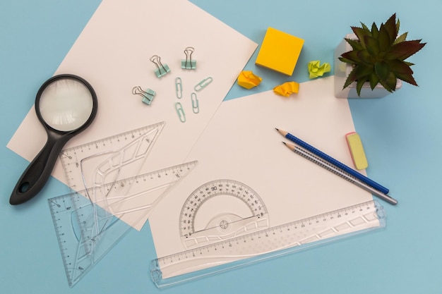 measuring and drawing tools a sheet of white paper pencils rulers on the desktop empty space for drawing or text on a blue background education or architectural concept flat layout