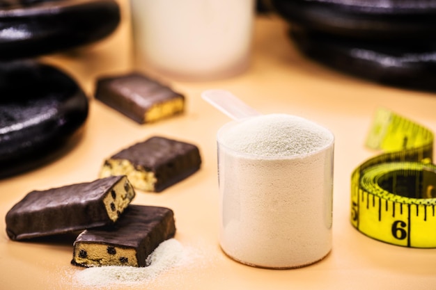 Мерная ложка с казеиновой сывороткой или протеиновыми батончиками со вкусом креатина и шоколада вокруг концепции диеты с измерительной лентой