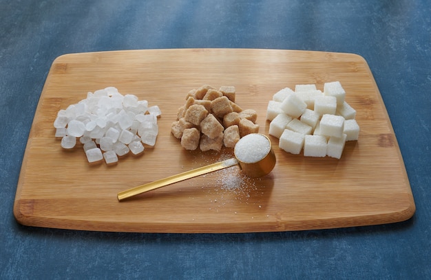 Measuring spoon with sugar sand, lump sugar on a bamboo board