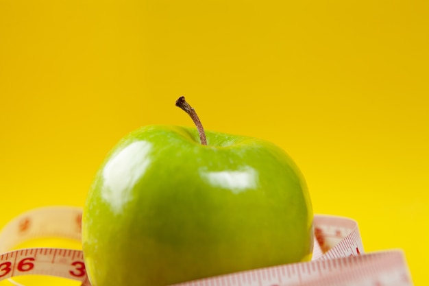 measuring tape and apples on a yellow background
