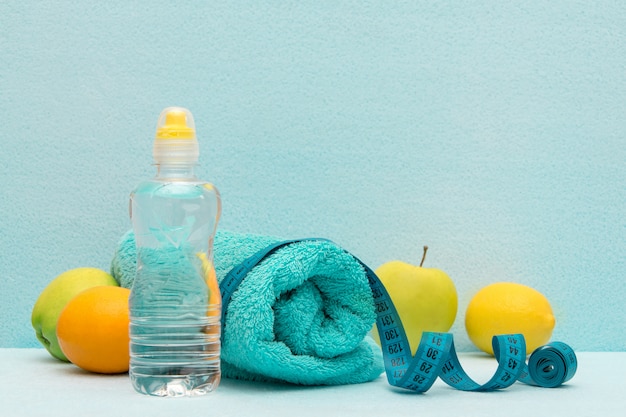 Measuring tape on a background of fruits, towels and a bottle of water.