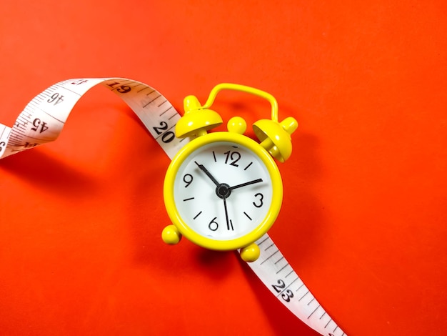 Measuring tape and clock on red background with copy space