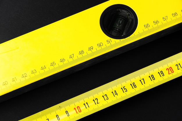 Measuring tape and construction level in yellow on a black background